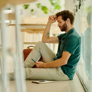 man sitting on floor with hand to head